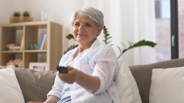 Senior femme avec télécommande regarder la télévision à la maison — Video