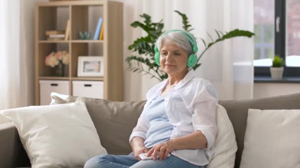 Äldre kvinna i hörlurar lyssna på musik — Stockvideo