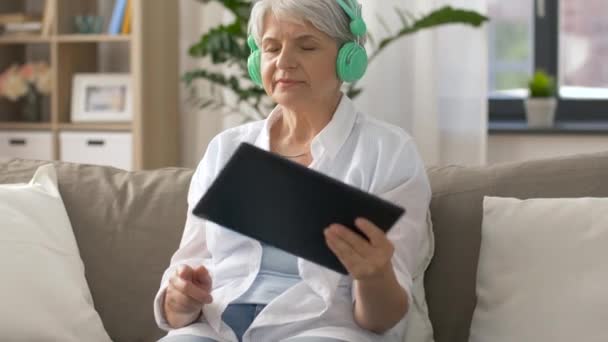 Старшая женщина в наушниках слушает музыку — стоковое видео