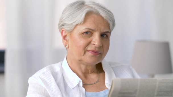 Portrait of senior woman reading newspaper at home — Stock Video