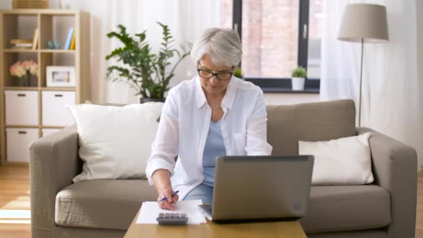 Senior Kvinna med laptop och kalkylatorn hemma — Stockvideo