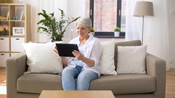 Glückliche Seniorin mit Tablet-PC zu Hause — Stockvideo