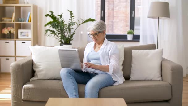 Lycklig senior kvinna att skriva på laptop hemma — Stockvideo