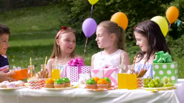 Счастливые дети с подарками на день рождения летом — стоковое видео