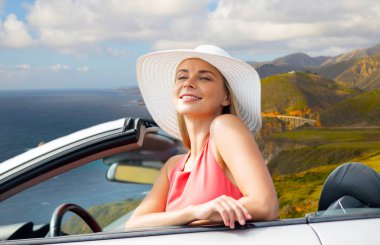 woman in hat in convertible car on big sur coast clipart