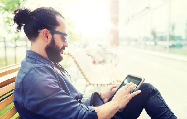 Uomo con tablet pc seduto sulla panchina della città — Foto Stock
