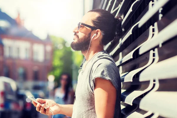 Happy man with earphones and smartphone in city — Stock Photo, Image