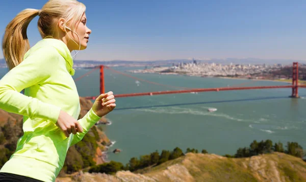 Mujer con auriculares corriendo sobre san francisco — Foto de Stock