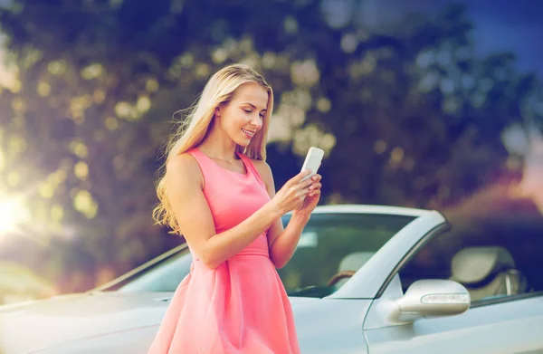 Junge Frau mit Smartphone am Cabrio — Stockfoto