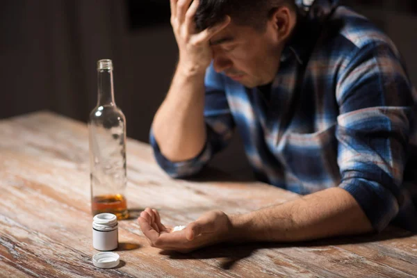 Hombre borracho infeliz con botella de alcohol y pastillas — Foto de Stock