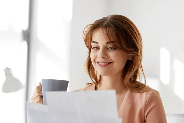 Zakenvrouw met papieren drinkt koffie op kantoor — Stockfoto