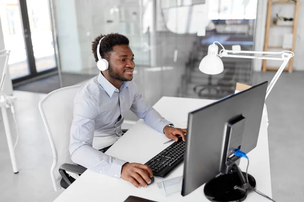 Homem de negócios com fones de ouvido e computador no escritório — Fotografia de Stock