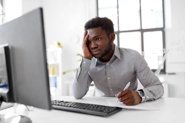 Homem de negócios com computador e papéis no escritório — Fotografia de Stock