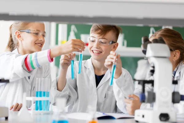 Niños con tubos de ensayo que estudian química en la escuela — Foto de Stock