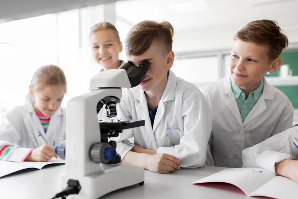 Crianças ou alunos com biologia microscópica na escola — Fotografia de Stock