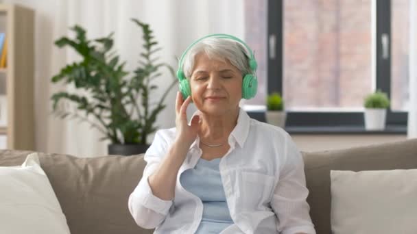Starší žena ve sluchátkách poslouchat hudbu — Stock video