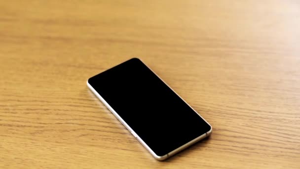 Smartphone con pantalla negra en blanco sobre mesa de madera — Vídeos de Stock