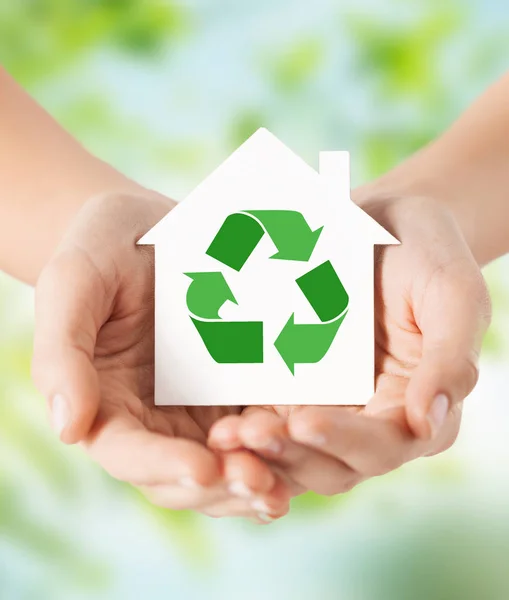 Руки тримають будинок з зеленим знаком переробки — стокове фото