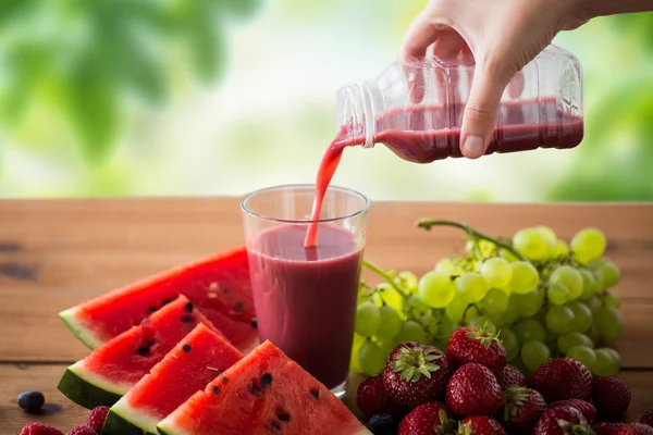 Ручной разлив фруктового сока из бутылки в стекло — стоковое фото