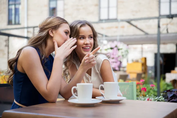 Hymyilevät nuoret naiset juovat kahvia ja juoruavat — kuvapankkivalokuva