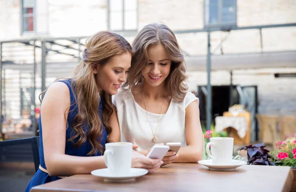 Mulheres jovens com smartphones e café no café — Fotografia de Stock