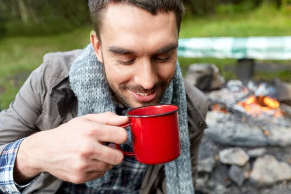 Крупный план улыбающегося мужчины, пьющего из чашки в лагере — стоковое фото