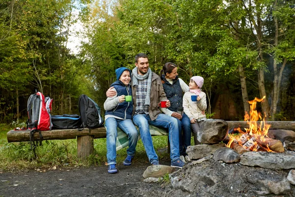 happy family drinking hot tea near camp fire
