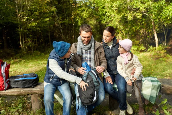Счастливая семья с рюкзаками и термосом в лагере — стоковое фото