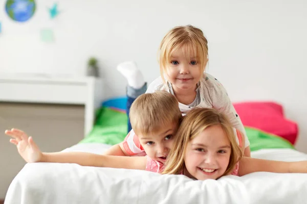 Mutlu küçük çocuklar eğleniyor evde yatakta — Stok fotoğraf