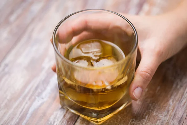 Manlig hand med glas alkohol på bord — Stockfoto