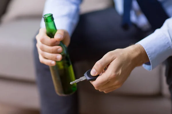 Mains de conducteur masculin tenant bouteille de bière et clé de voiture — Photo