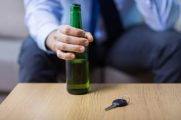 Mano maschile con bottiglia di birra e chiave della macchina sul tavolo — Foto Stock