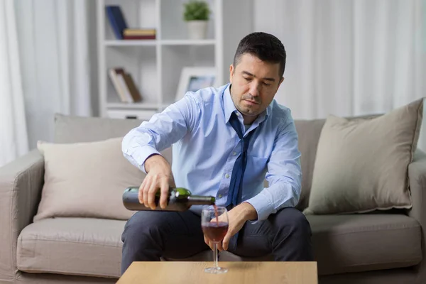 Alkoholiker schenkt zu Hause Rotwein ins Glas ein — Stockfoto