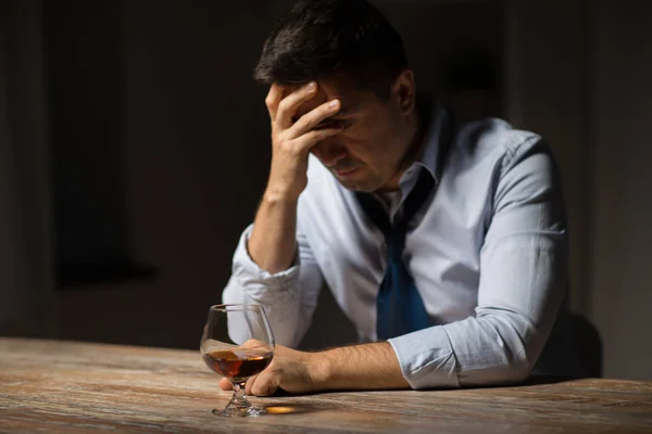 Uomo ubriaco con bicchiere di alcol sul tavolo di notte — Foto Stock