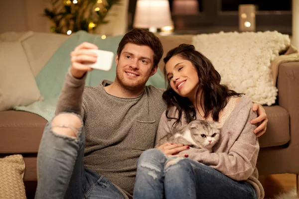 Feliz pareja tomando selfie por teléfono inteligente en casa —  Fotos de Stock