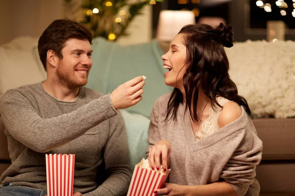 Feliz pareja comiendo palomitas de maíz en casa —  Fotos de Stock