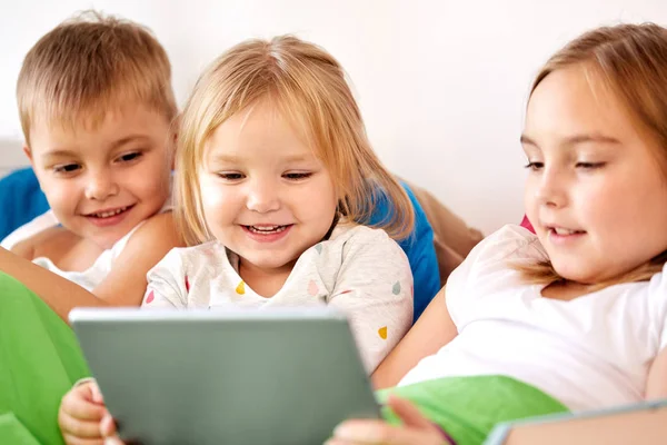 Happy little kids with tablet pc in bed at home — Stock Photo, Image