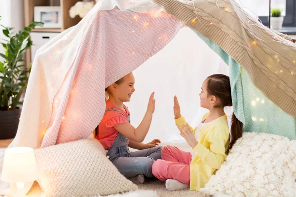 Девочки играют в аплодисменты в детской палатке дома — стоковое фото