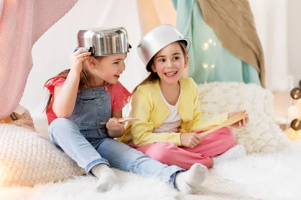 Девушки с кухонной утварью играют в палатке дома — стоковое фото