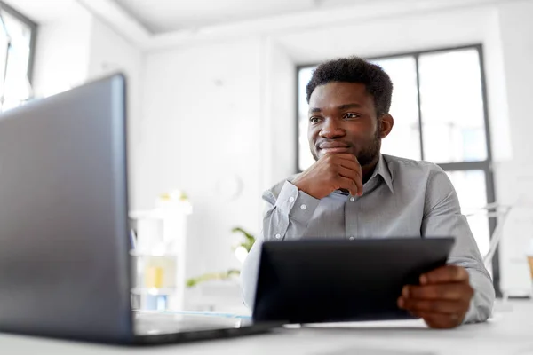 Hombre de negocios con ordenador portátil y tableta PC en la oficina — Foto de Stock