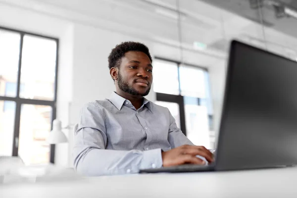 Empresário afro-americano com laptop no escritório — Fotografia de Stock