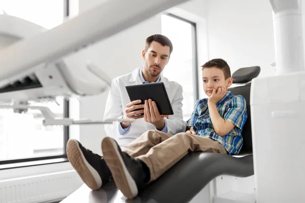 Dentista mostrando tablet pc para paciente criança na clínica — Fotografia de Stock