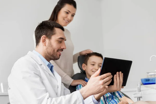 Dentista mostrando tablet pc para criança na clínica odontológica — Fotografia de Stock