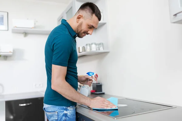 Uomo con straccio pulizia fornello a casa cucina — Foto Stock
