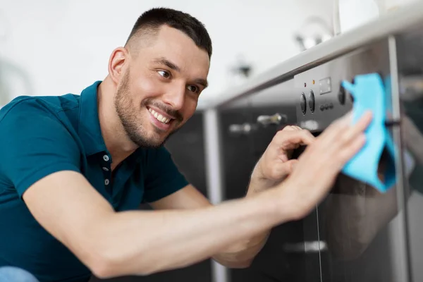 Uomo con straccio pulizia forno porta a casa cucina — Foto Stock