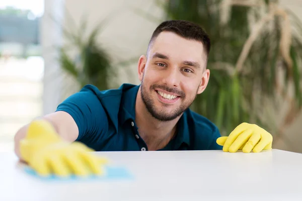 Smiling man cleaning table with cloth at home — Stock Photo, Image