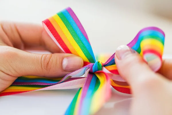 Mãos amarrando arco de gay orgulho consciência fita — Fotografia de Stock