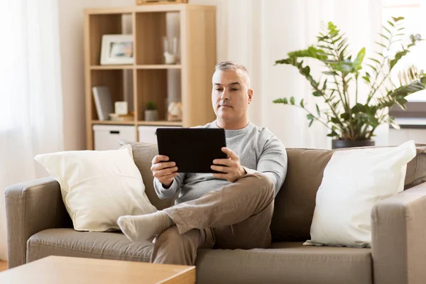 Homme avec tablette PC assis sur le canapé à la maison — Photo