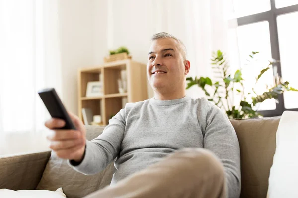 Man med fjärrkontroll tittar på TV hemma — Stockfoto