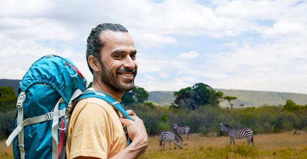 Uomo sorridente con zaino sopra savana africana — Foto Stock